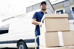 Agent de déménagement chargeant des cartons sur chariot devant un camion, assurance déménagement Demeco assurant la protection des biens.