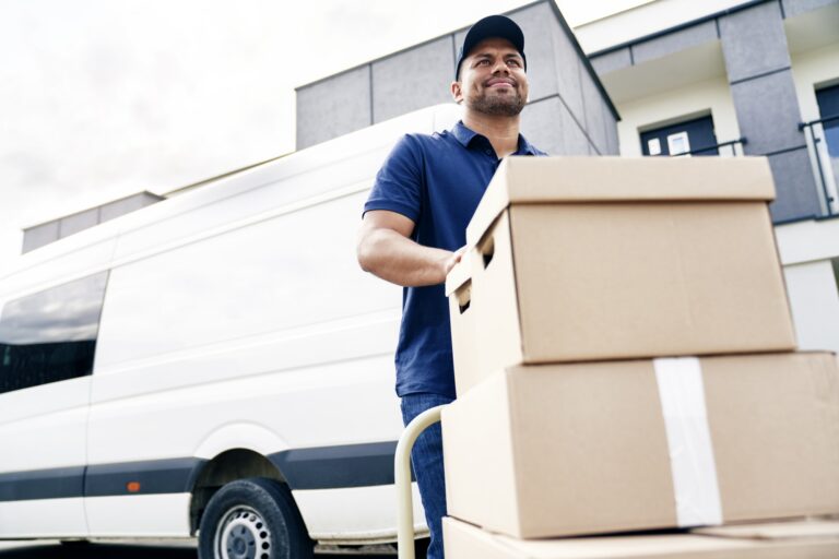 Agent de déménagement chargeant des cartons sur chariot devant un camion, assurance déménagement Demeco assurant la protection des biens.